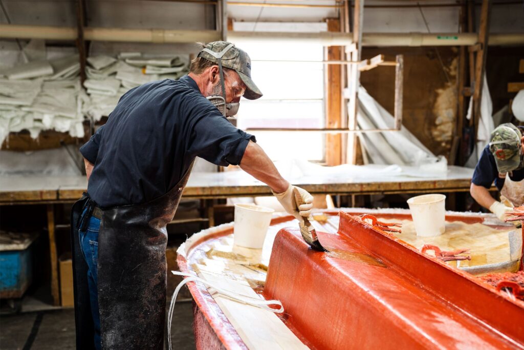 man staining a sailboat