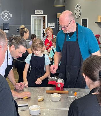 A man teaching people how to mix dough.