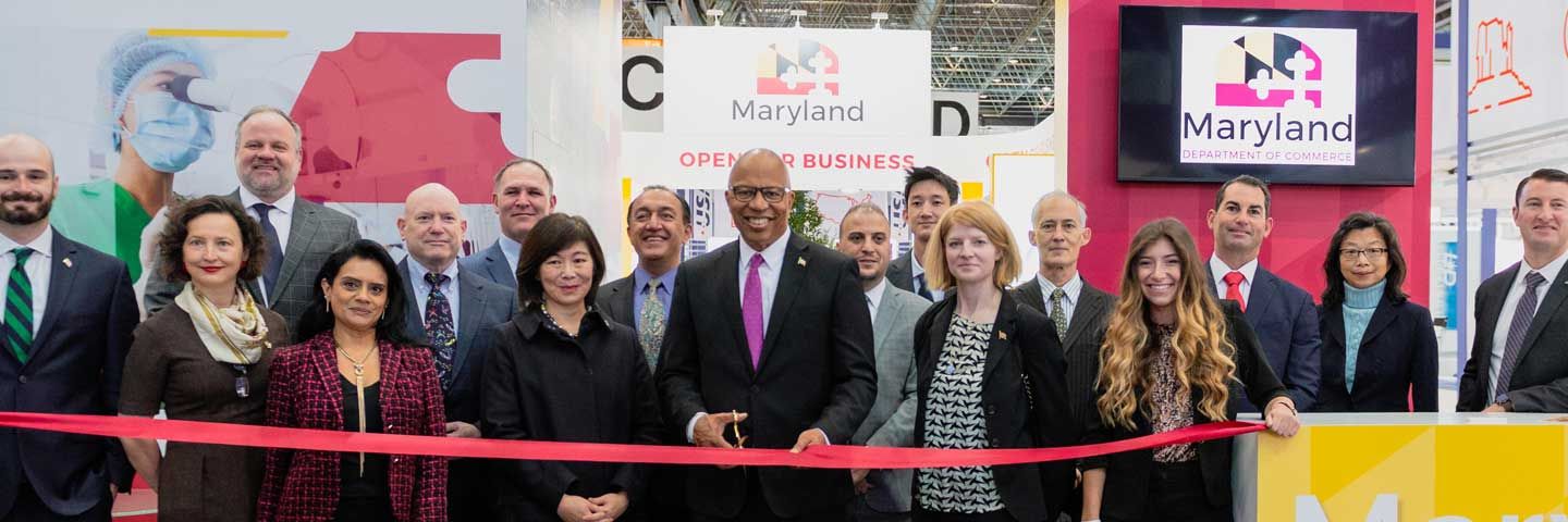 Group of people standing at ribbon cutting smiling