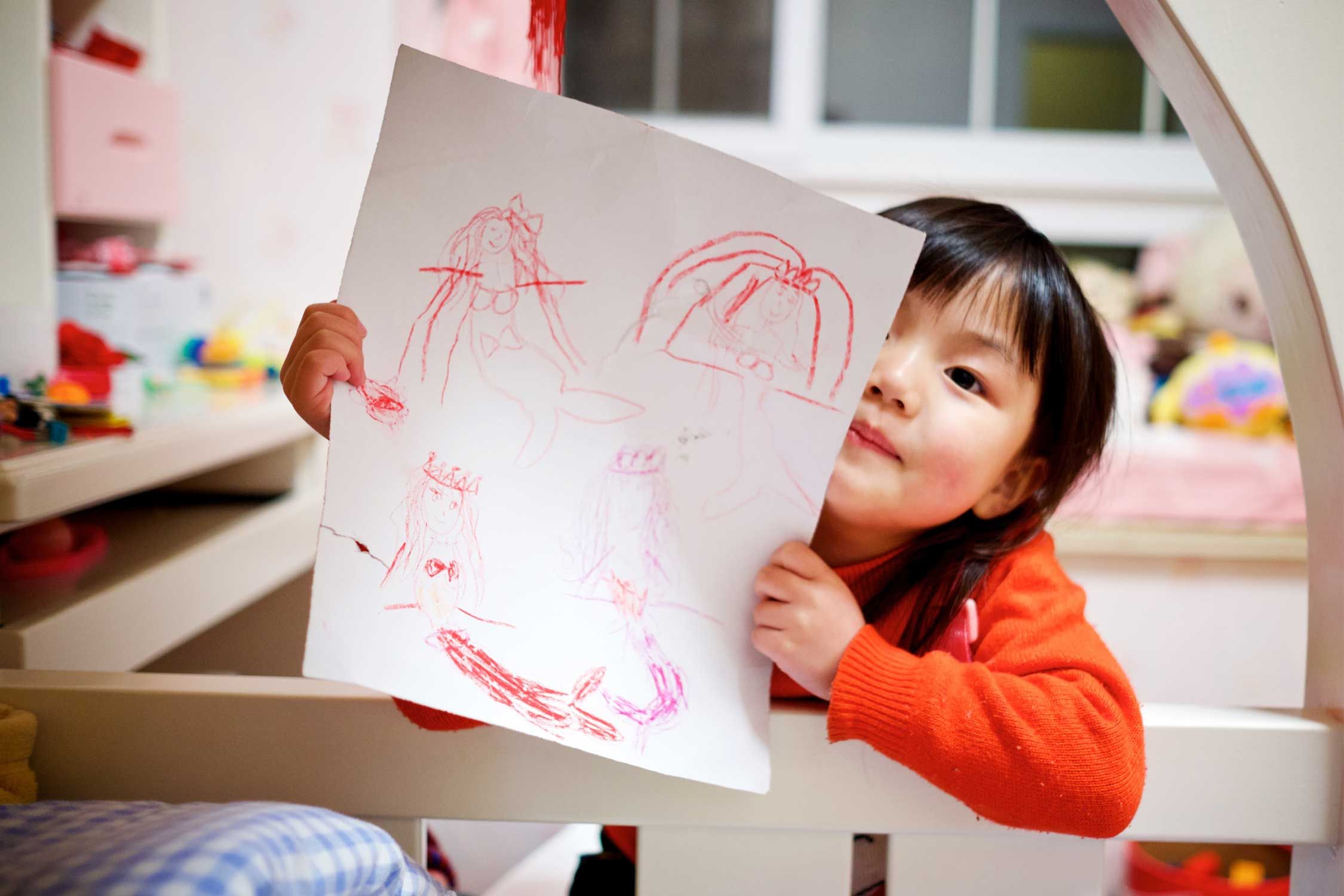 child holding mermaid drawings