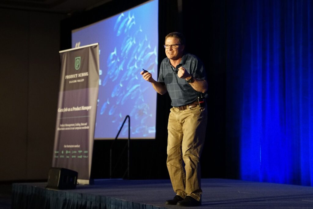 Man presenting on stage at a conference