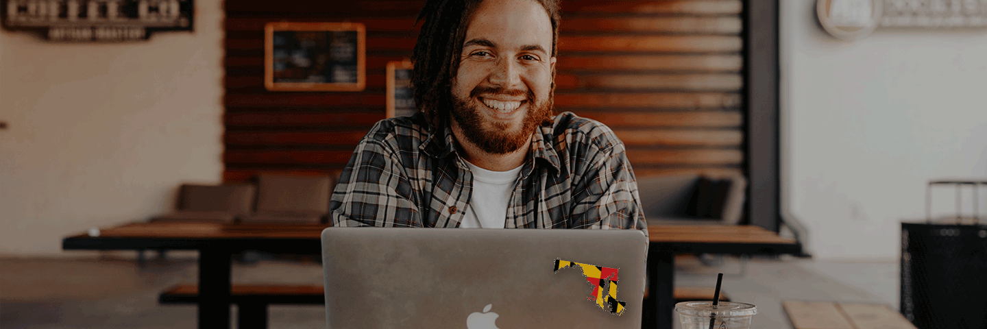 Man working on laptop with state of Maryland sticker