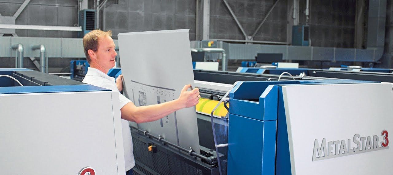 Man working on a large metal printer