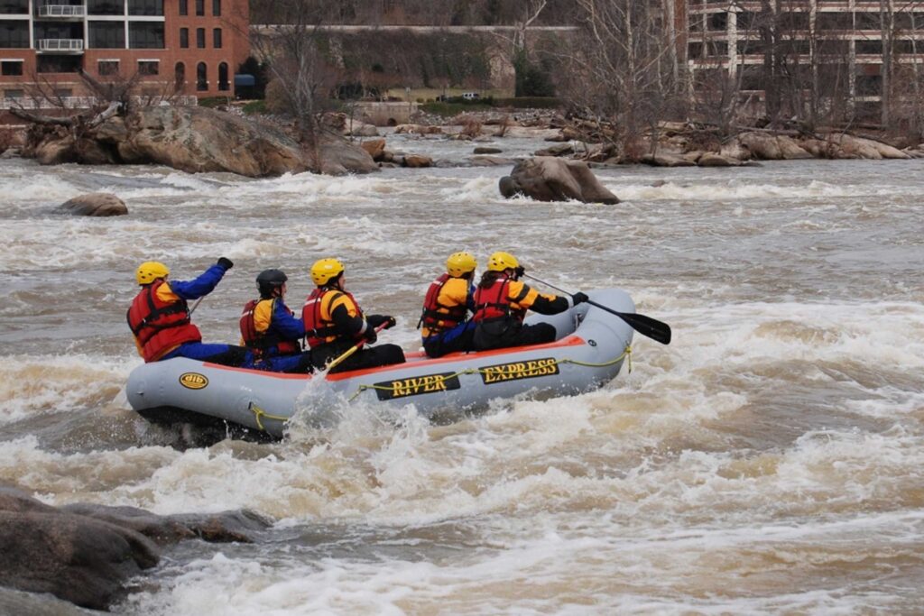 five individuals rafting down a rapid river in an inflatable boat
