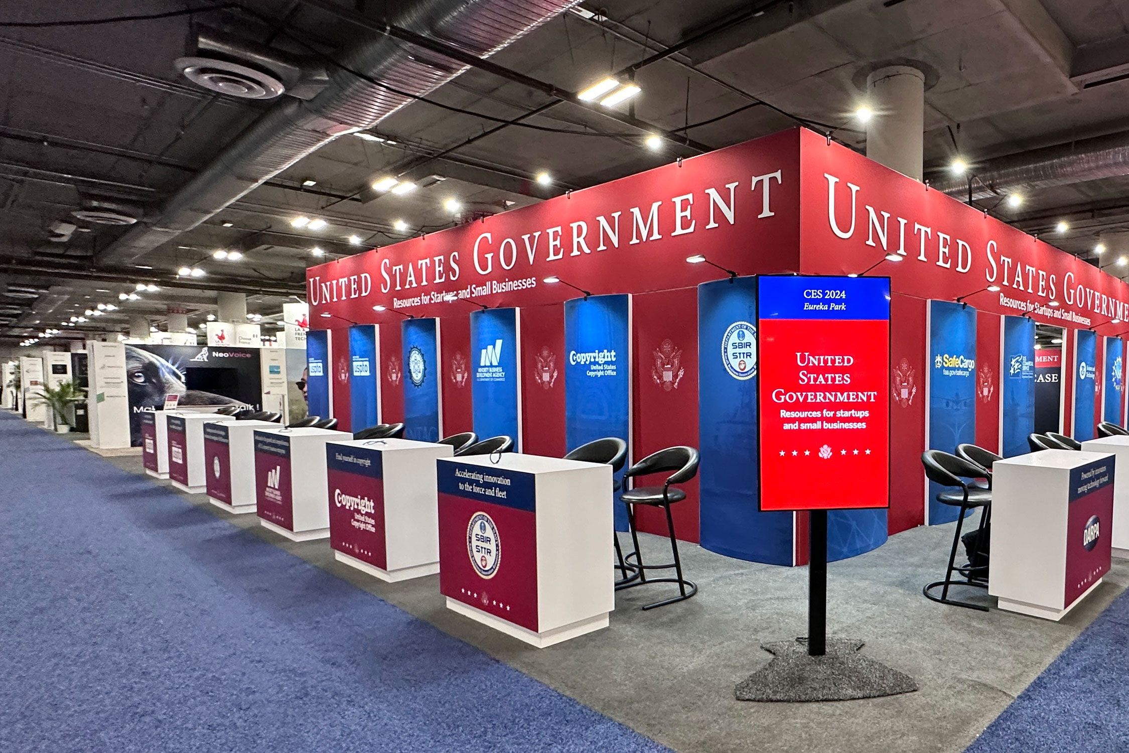A large trade show booth with several small stands and chairs next to them