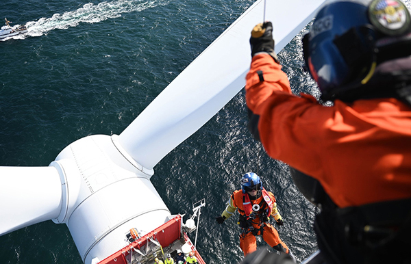 People on an ocean windmill doing repairs

