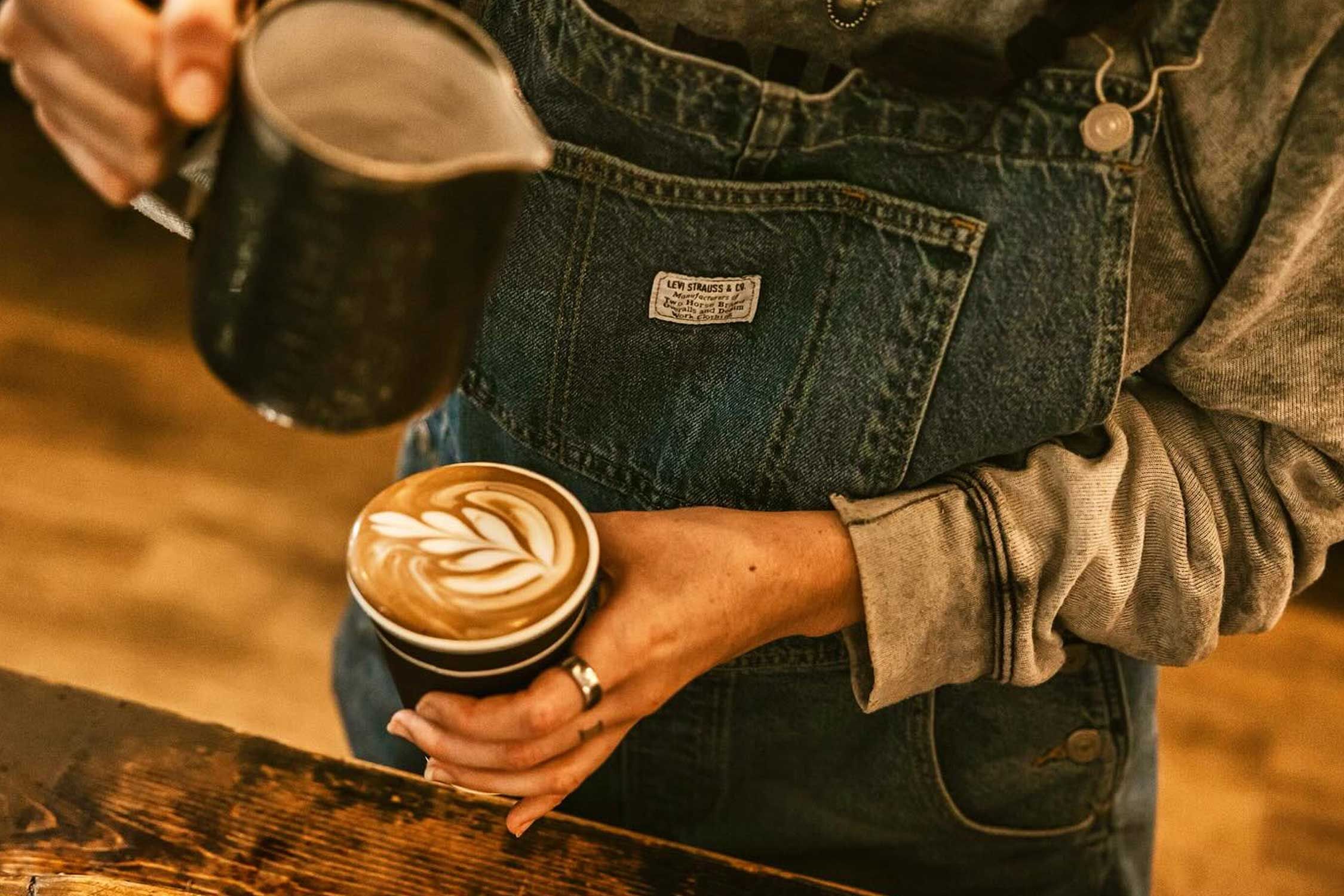 a barista making latte art in a coffee cup