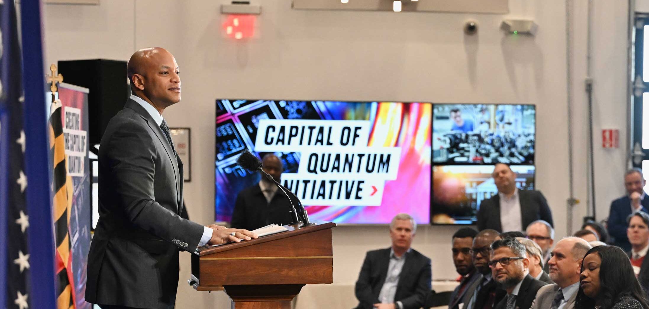 Governor Moore presenting to a group in front of a sign that says Capital of Quantum Initative