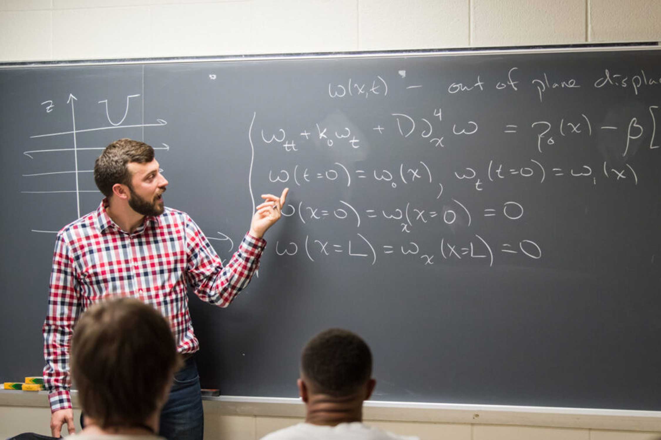 a math teacher writes on a chalkboard