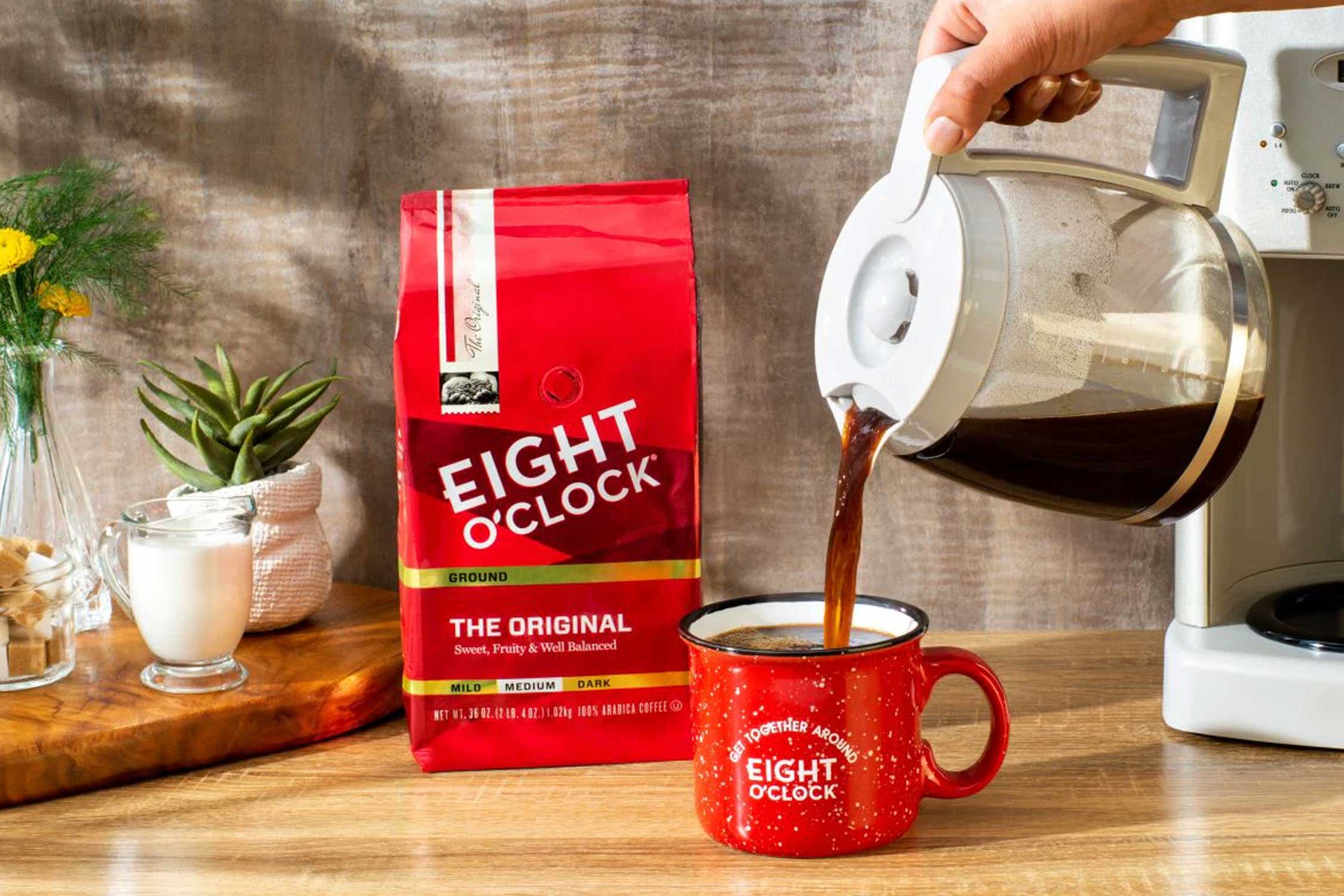 a hand pouring a coffee pot of Eight O'Clock Coffee