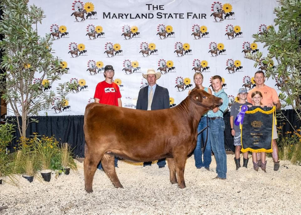 A family stands behind a cow while presenting it at the Maryland State Fair.