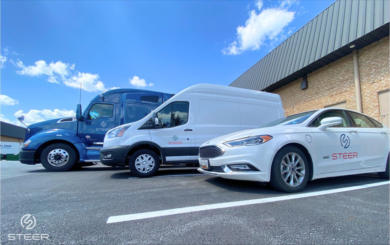 3 autonomous vehicles (blue truck, white van, and white car) lined up