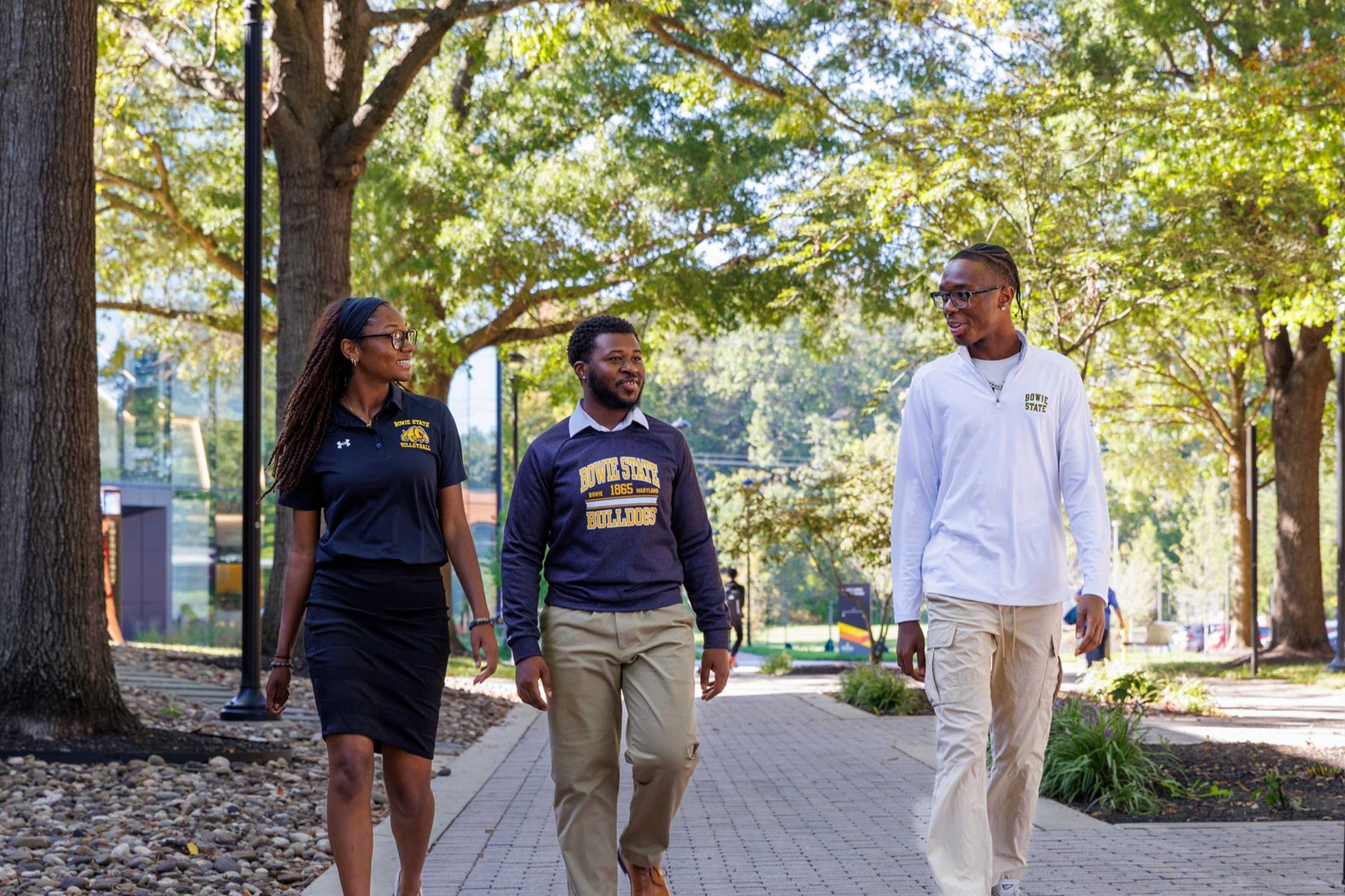 three students walking under trees on bowie state university's campus